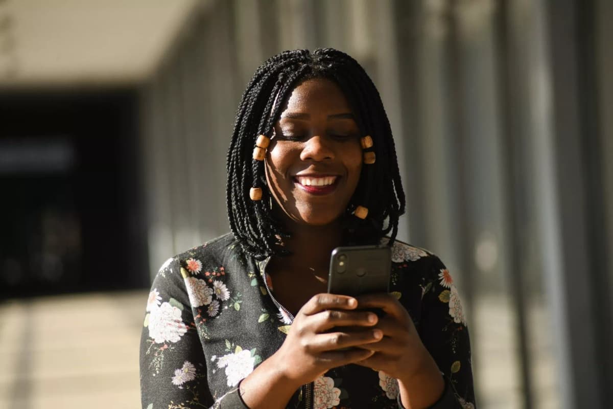 A woman smiling as she looks at her phone